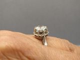 la main d'une personne tenant une bague en argent sur laquelle est représenté un chat