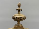 a gold vase with a bird on top of it