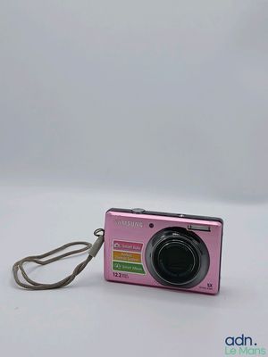a small pink camera with a strap on it