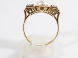 a close up of a gold ring with a pearl and diamonds
