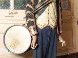 a statue of a man in a uniform with a drum in front of a window