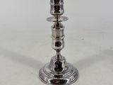 two silver candlesticks on a white surface