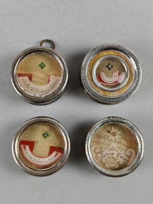 quatre petits boutons en métal sur lesquels est représenté un ours en peluche