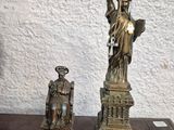 statue of liberty and a clock sitting on a table in front of a white wall