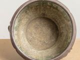 a metal bowl sitting on a table with a white wall in the background
