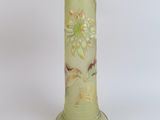 a green vase with flowers on it on a white background