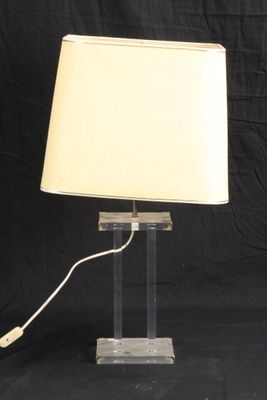 une lampe de table en acrylique transparent, surmontée d'un abat-jour blanc