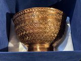 a gold bowl sitting in a blue box on a table