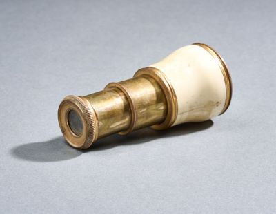 un télescope doré et blanc posé sur une surface grise