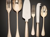several forks and spoons are lined up on a black surface