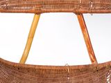 a wicker chair with two wooden legs and a basket on the back of it