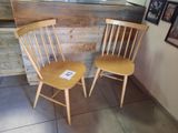 two wooden chairs sitting next to each other in a room