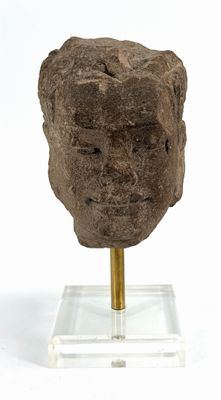 an image of a stone head on a stand on a white surface