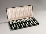 six silver spoons in a case on a table