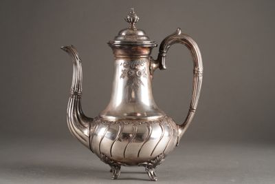 a silver tea pot on a stand on a gray surface