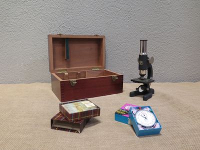 a wooden box with a clock, books, and a microscope on a table