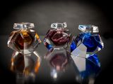 trois flacons de parfum posés sur une table, sur fond noir