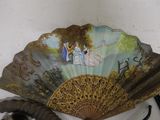 a fan with a painting on it next to a pair of scissors