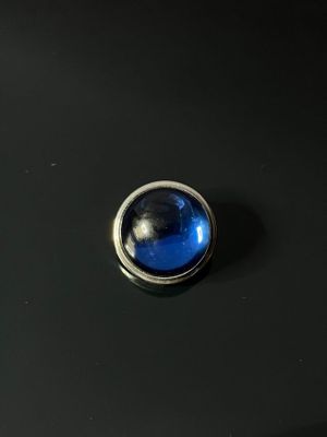 a close up of a blue button on a black surface