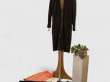 a mannequin and a pair of pants next to a plant
