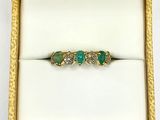 an image of a diamond and emerald ring in a gold box