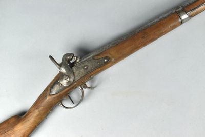 un vieux pistolet avec une poignée en bois sur une surface blanche
