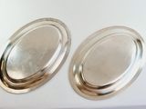 pair of silver oval trays on a white surface