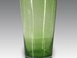 le verre vert est posé sur la table devant un fond gris