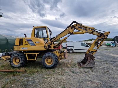 un tracteur jaune garé sur la terre battue