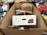 de nombreux cartons contenant des vêtements et d'autres objets, posés par terre