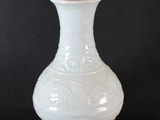 un vase blanc posé sur un socle en bois
