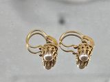 pair of gold earrings with pearls on them sitting on a table