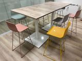 Des chaises aux couleurs vives sont disposées autour d'une table en bois dans une salle de réunion