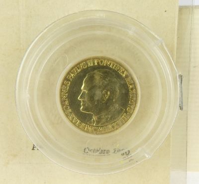 a gold coin in a clear plastic container on a table