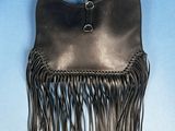 black leather purse with fringes hanging on a blue background