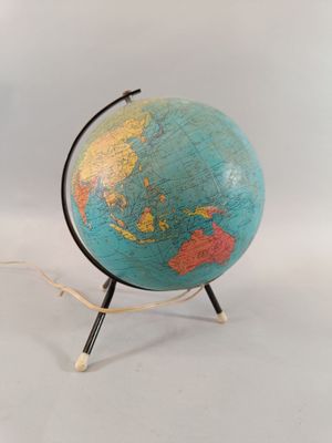 un petit globe posé sur un socle, sur une surface blanche
