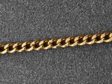 a close up of a gold chain bracelet on a gray surface