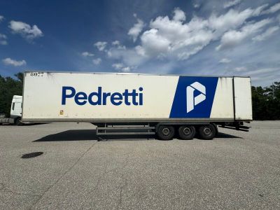 a white semi trailer parked in a parking lot with a blue and white logo on the side