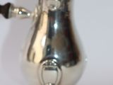 a silver coffee pot with a handle on a stand