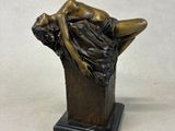 bronze statue of a woman laying on a tree trunk