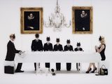 a man and woman standing in front of a table with a group of people dressed in black