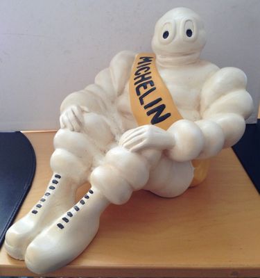 a statue of a man sitting on a desk with a ribbon around his neck