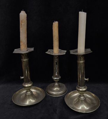 three silver candles sitting on top of a table next to each other
