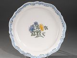 un gros plan d'une assiette blanche ornée de fleurs bleues et jaunes