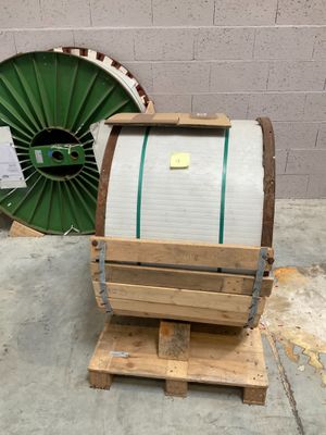 a wooden barrel sitting on top of a pallet next to a green wheel