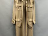 un manteau beige suspendu à un cintre devant un mur gris