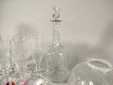 bottles and glasses are sitting on a table with a flower in a vase