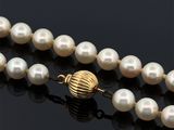 gros plan d'un collier de perles sur une surface noire