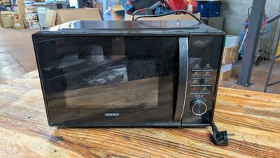 un micro-ondes noir posé sur une table en bois dans un entrepôt
