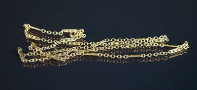 gros plan d'un bracelet en chaîne en or sur une surface noire